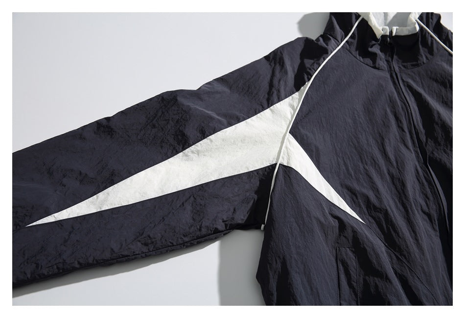 Close-up of the navy windbreaker’s sleeve with a long white accent panel and front piping.