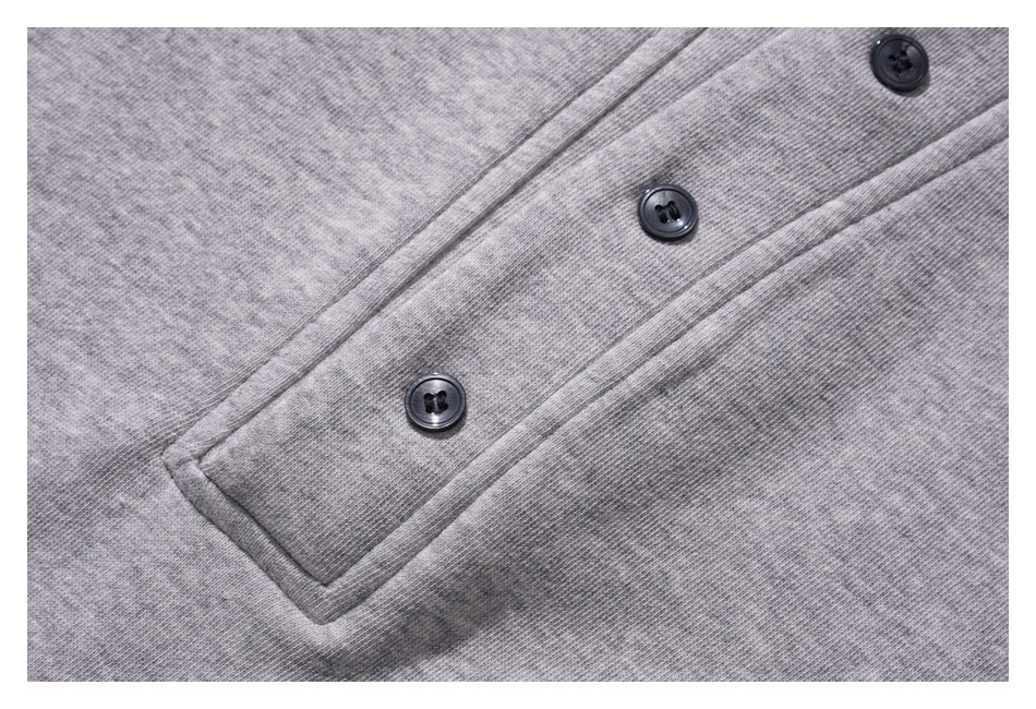 Close-up of the gray sweatshirt's stitched placket with three dark buttons.
