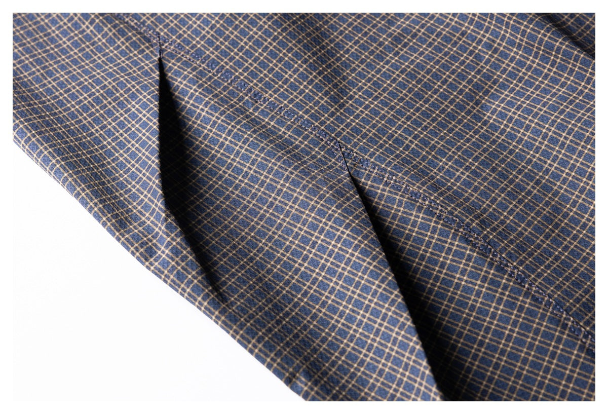 Close-up of navy and tan plaid garment fabric with a diagonal stitched seam.
