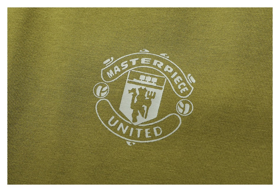 Close-up of a white crest graphic reading “MASTERPIECE UNITED” printed on olive fabric.