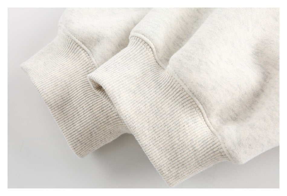 Close-up of two ivory heather sweatshirt cuffs with fine ribbed trim.