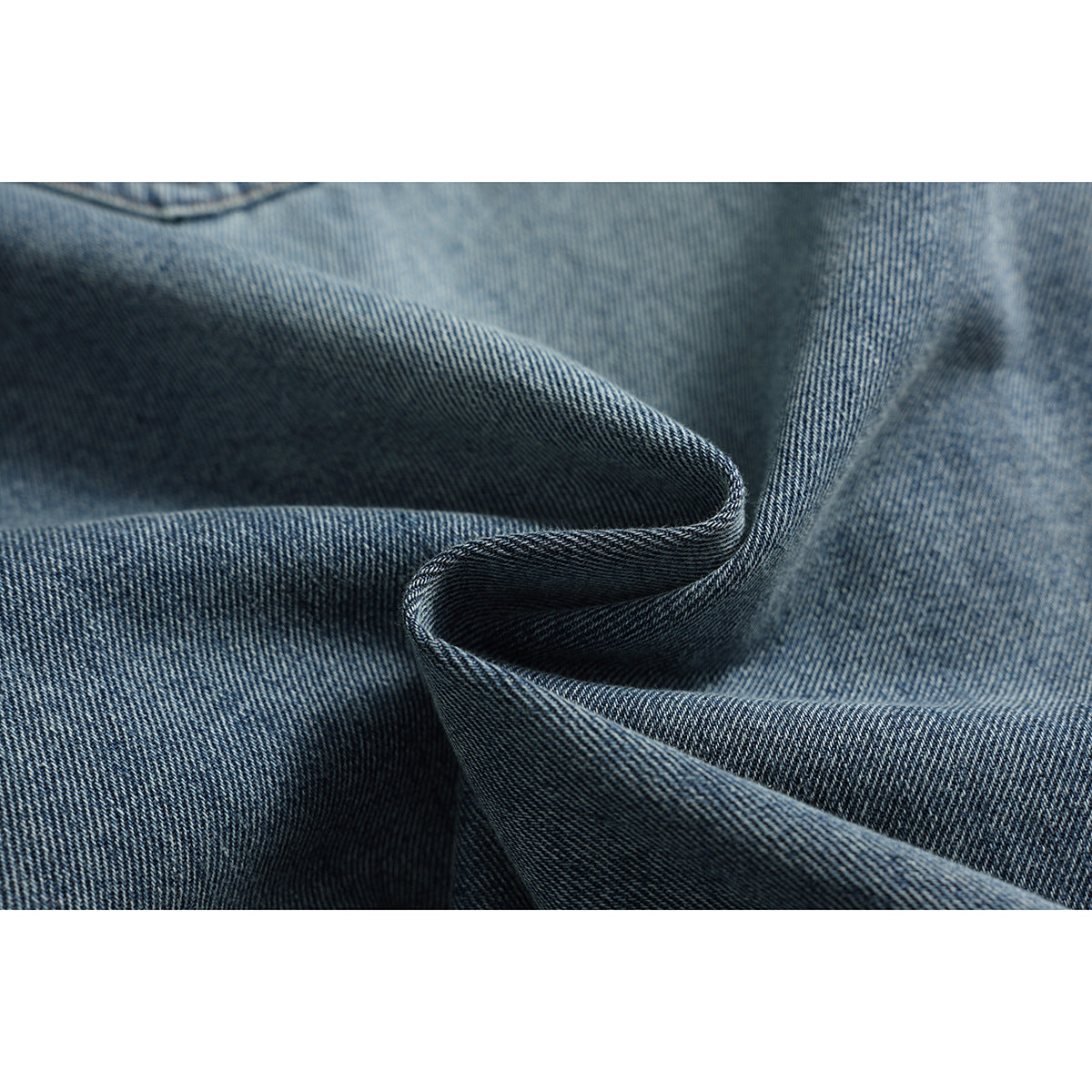 Macro view of blue denim folded to show its diagonal weave and textured surface.