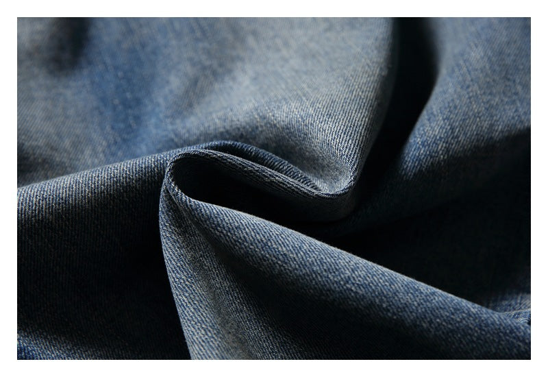 Close-up of blue denim fabric with a visible diagonal weave and soft folds.