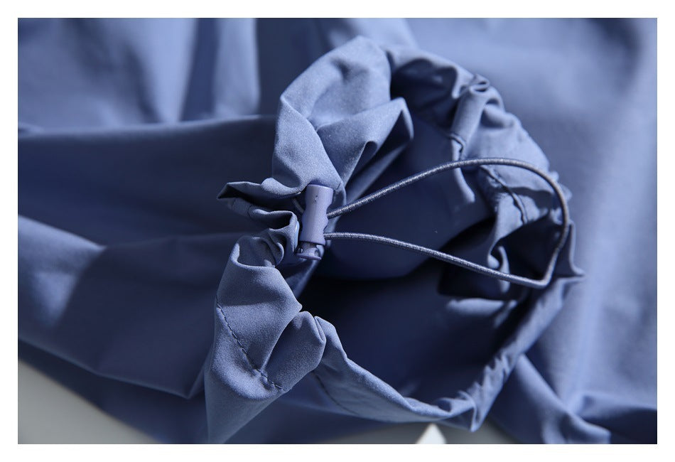 Close-up of a blue garment's drawcord and toggle at a gathered opening.