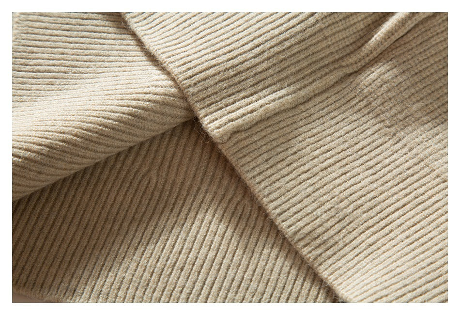 Close-up of overlapping beige sweater knit showing the ribbed texture and seam construction.