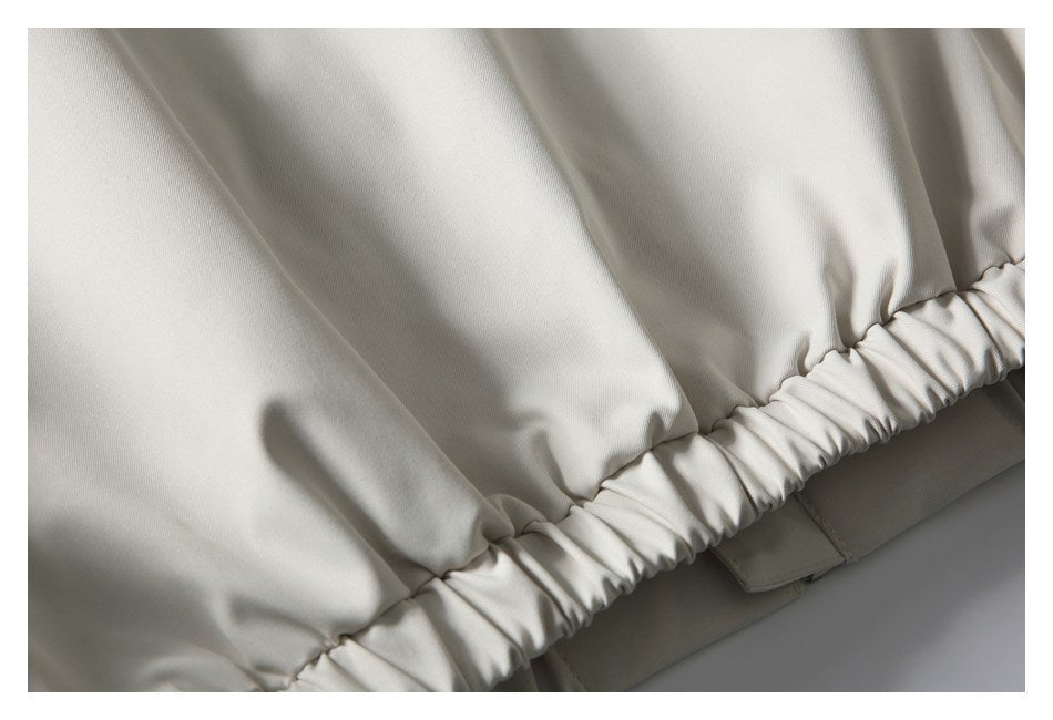 Close-up of light beige garment fabric gathered into a ruched elastic edge.