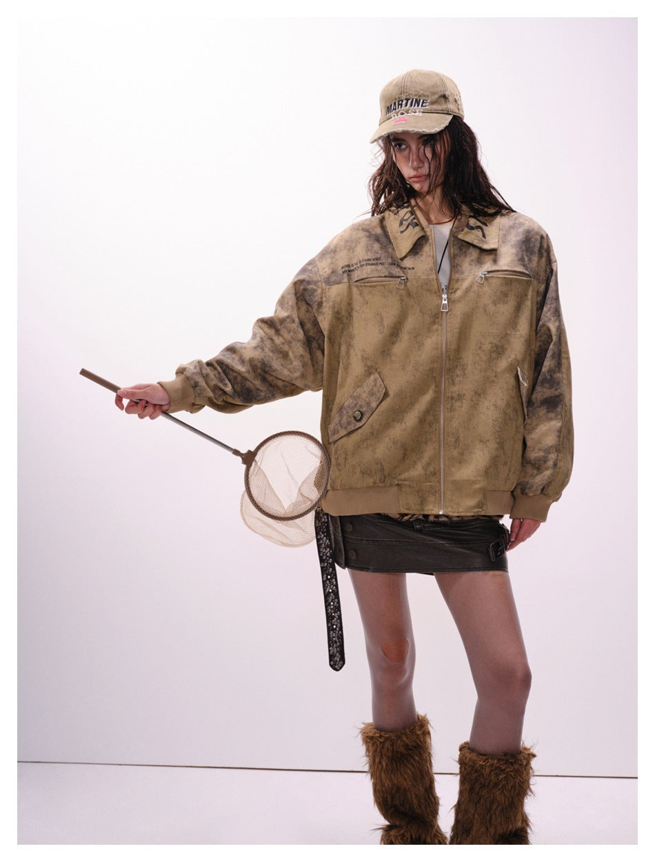 Model wearing a mottled tan-brown zip jacket with darker sleeves, chest zips, a pointed collar and ribbed trim.