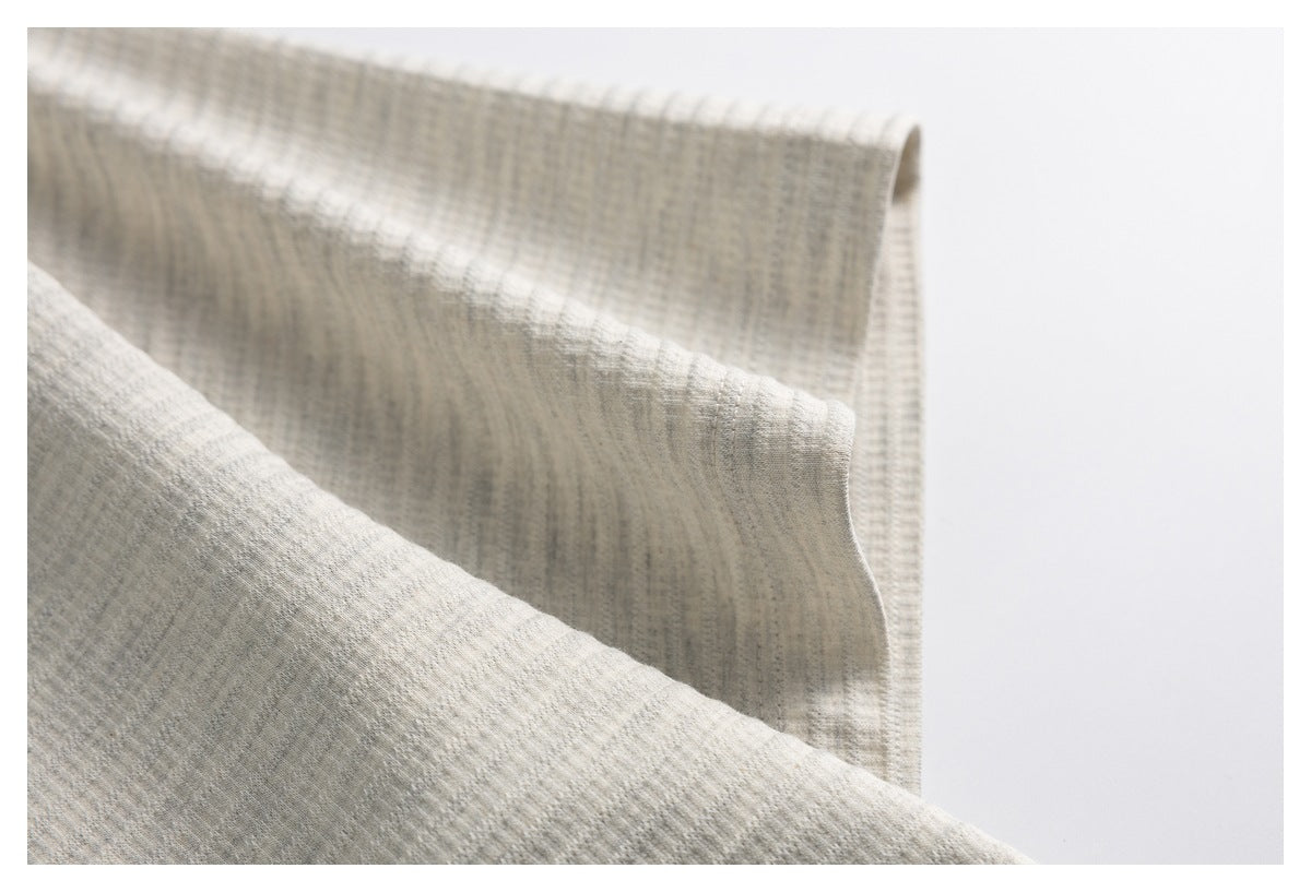 Close-up of light heather-gray knit fabric folded to show its subtle textured pattern.
