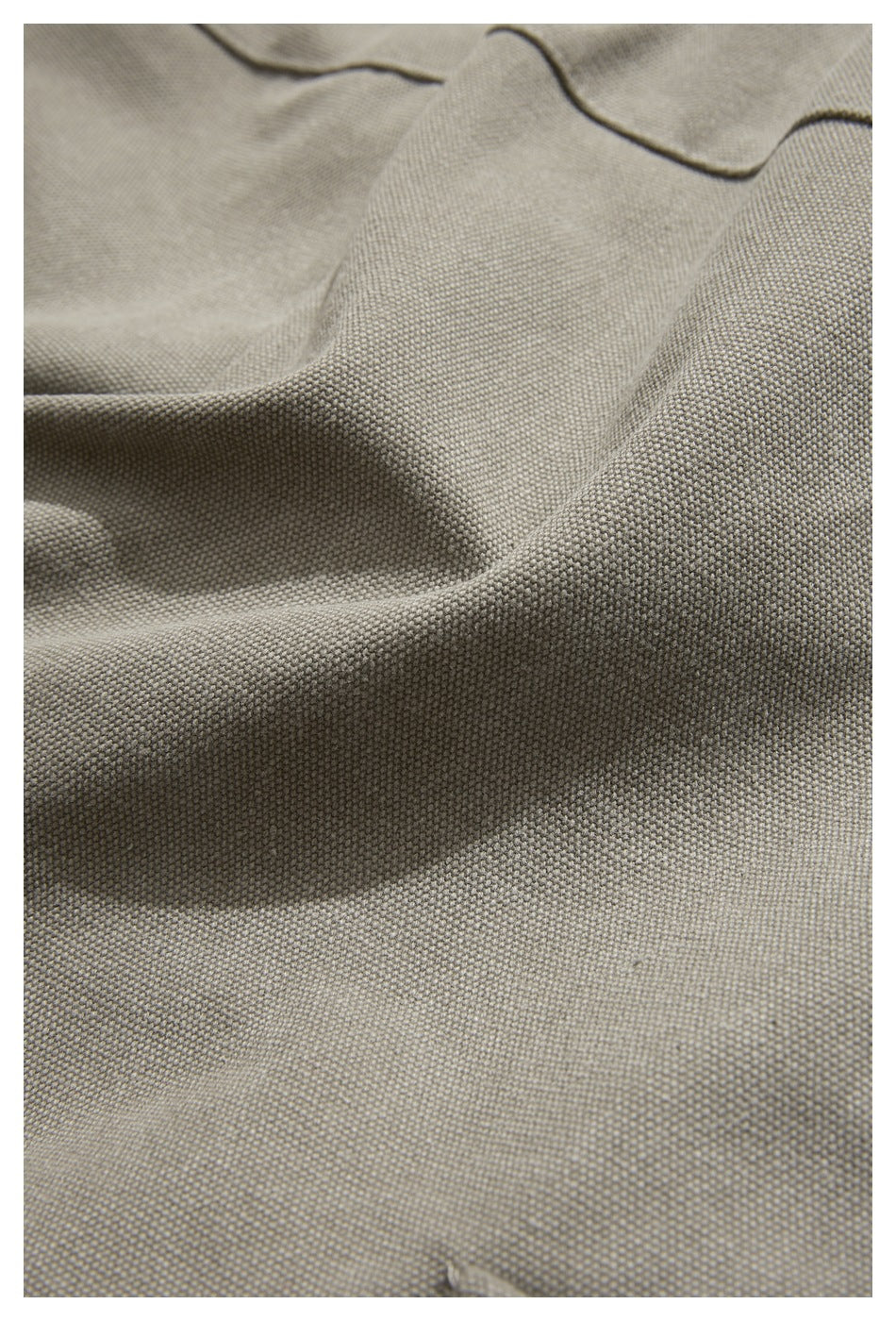 Extreme close-up of the textured taupe-gray trouser fabric and stitching.