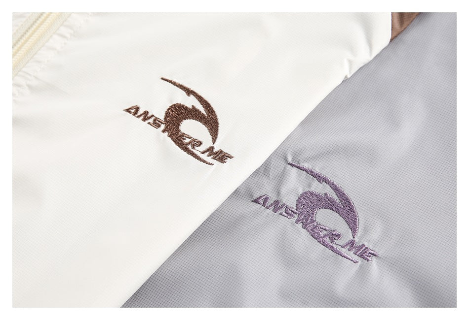 Close-up of embroidered logos on white and light gray jacket panels.