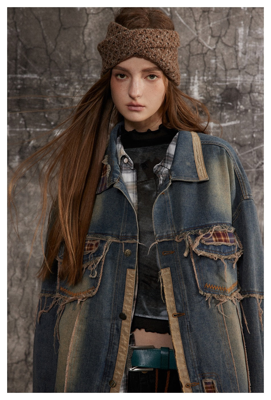 Front view of a model wearing an oversized blue denim jacket with frayed plaid patch pockets and tan trim.