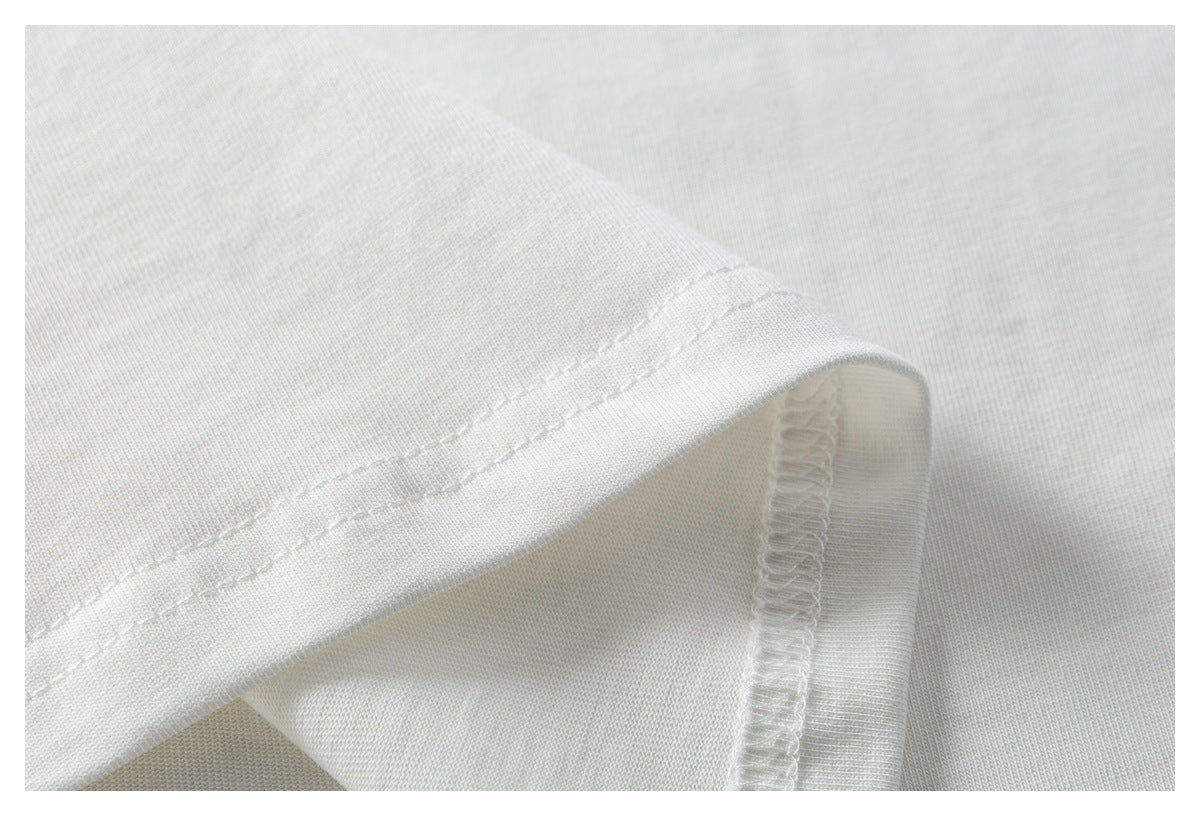 Close-up of white garment fabric showing a folded hem with double stitching and an overlocked seam.