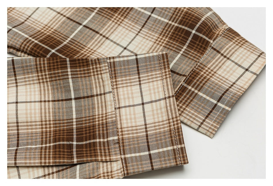 Close-up of a brown and cream plaid shirt cuff and sleeve stitching.