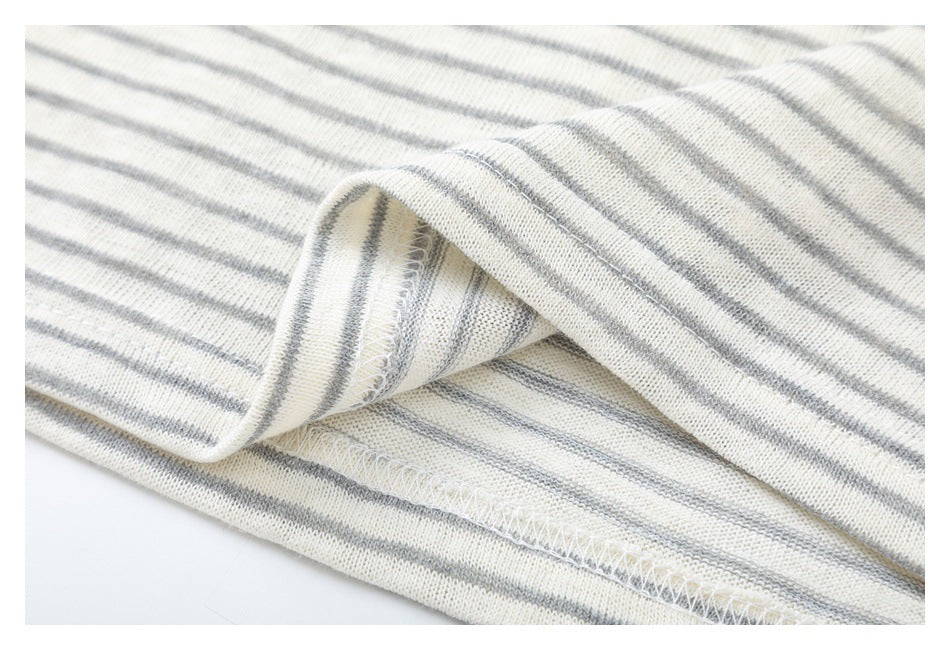 Close-up of cream-and-gray striped knit fabric showing a folded edge and overlock stitching.