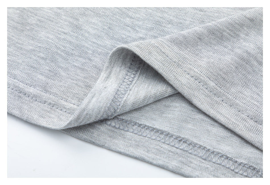 Close-up of a light gray garment hem showing the folded edge and overlock stitching.