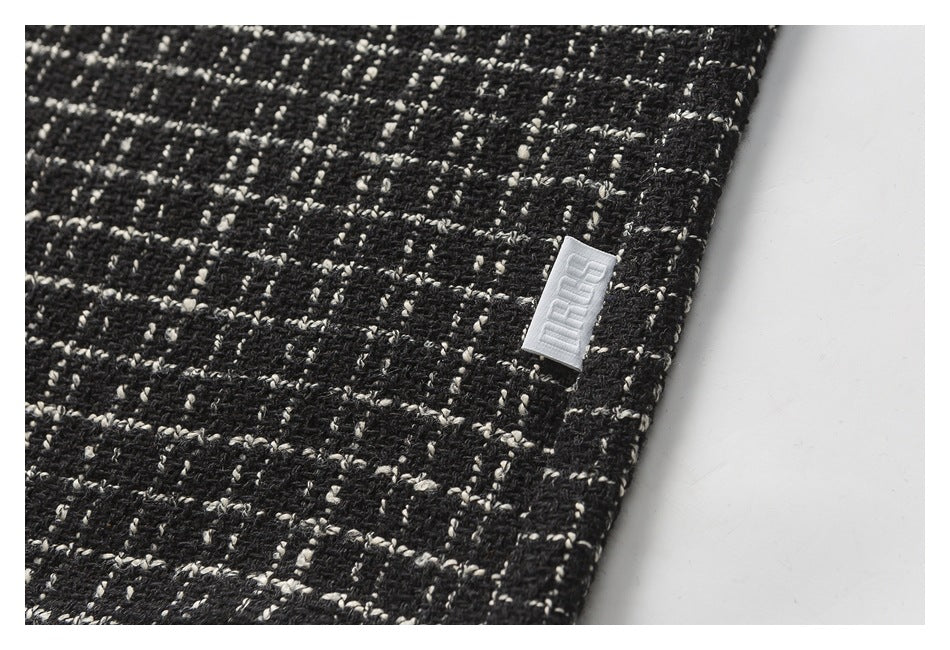 Close-up of black-and-cream textured fabric with a small white woven label.
