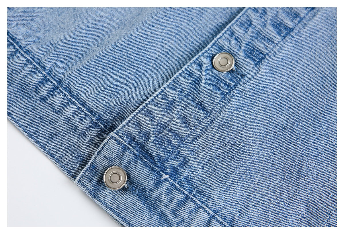 Close-up of two round metal snaps and stitched seams on light blue denim.