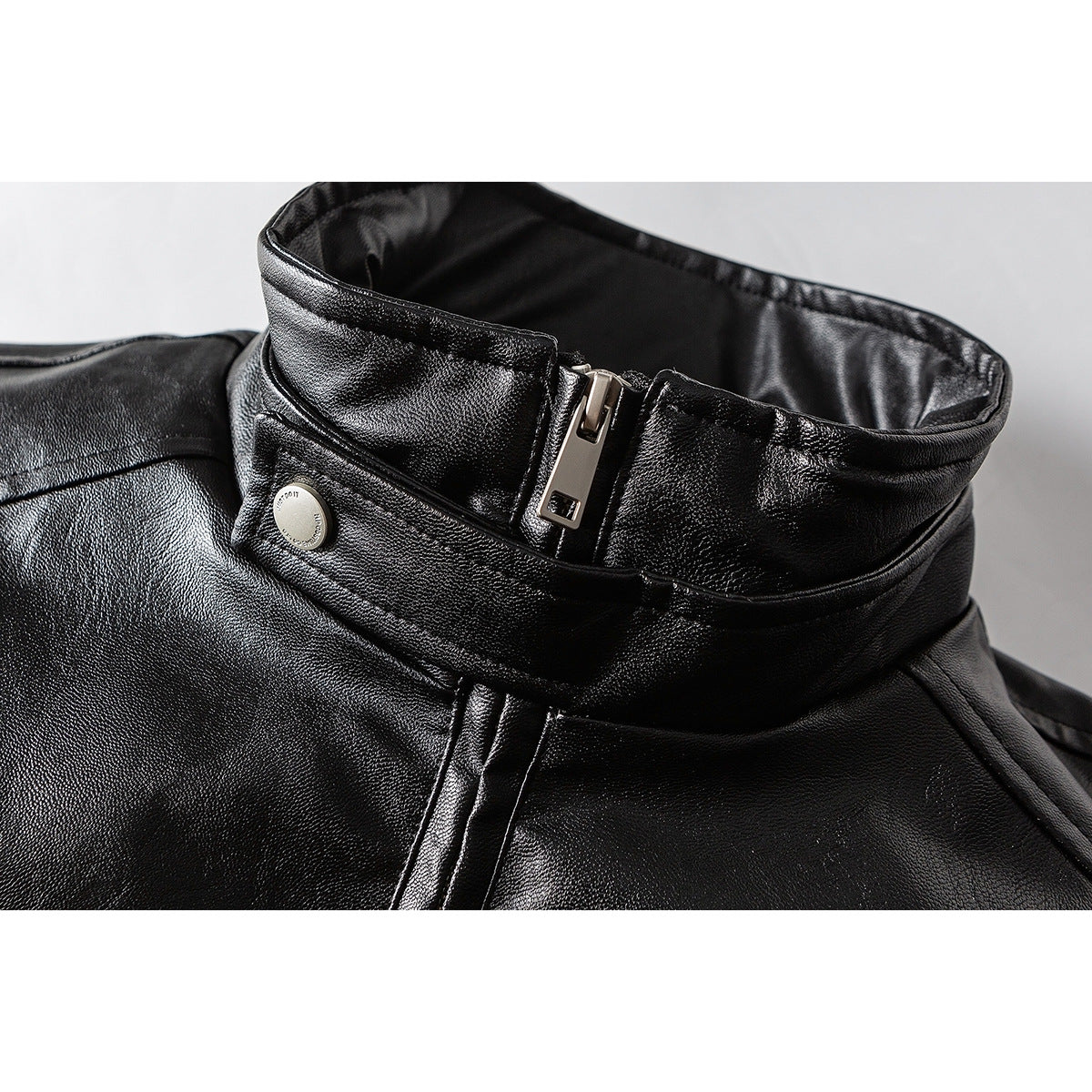 Close-up of a black jacket collar with a silver zipper and snap button.