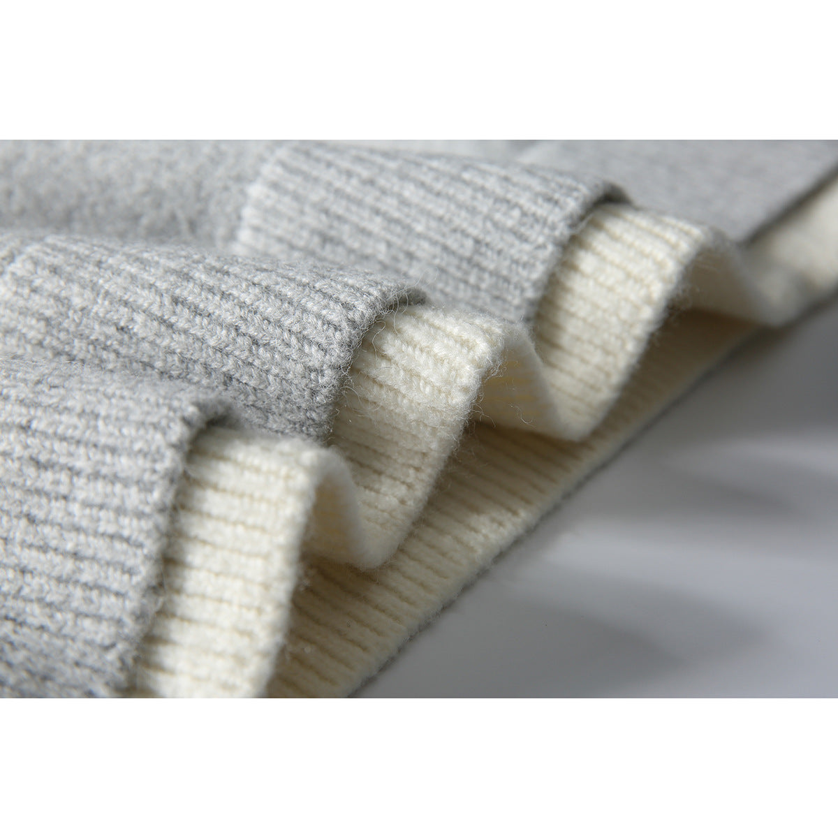 Macro view of gray and cream knit layers with ribbed edges and visible stitching.