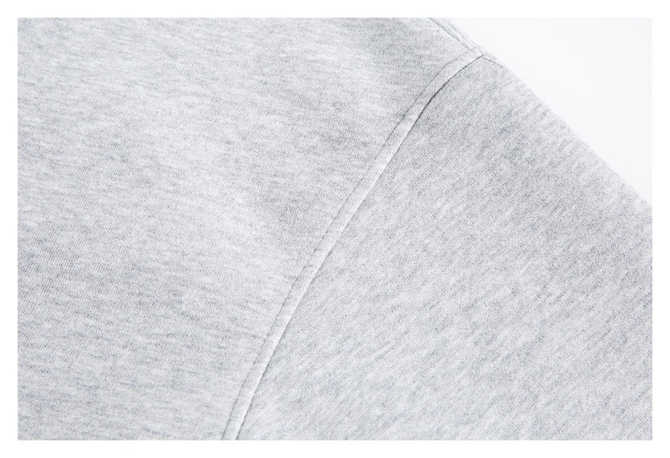 Close-up of a light gray hoodie’s shoulder seam and heathered fabric.