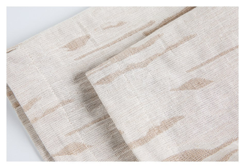 Close-up of a folded, stitched edge on cream fabric with tan abstract streaks.