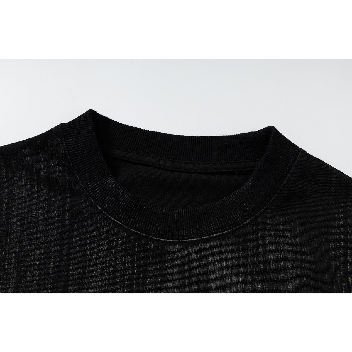 Close-up of a black T-shirt's ribbed crew neck and subtly streaked fabric.
