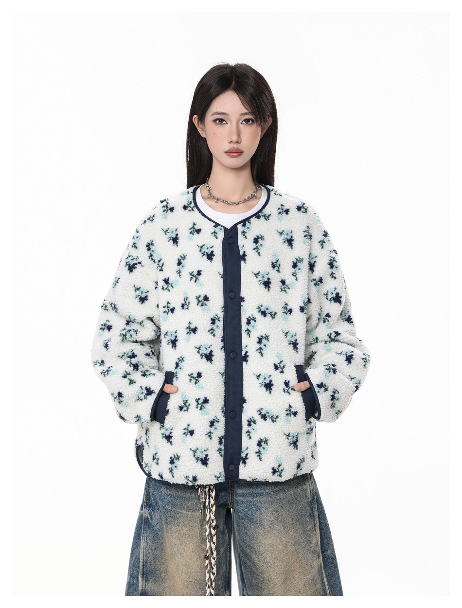 Model wearing a cream sherpa jacket with scattered teal and navy floral print, dark trim, snap buttons and pockets.
