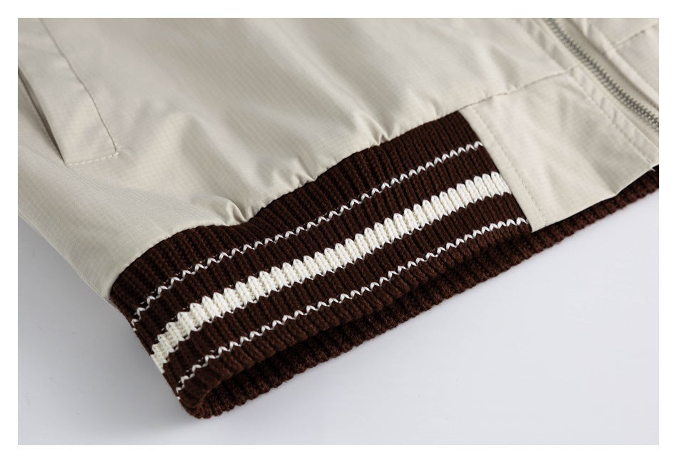 Close-up of the cream jacket's dark brown ribbed hem with white stripes.