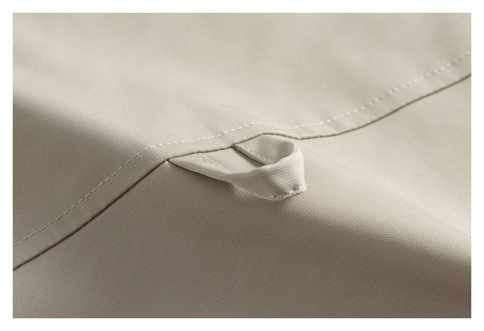 Close-up of a small beige fabric loop secured along a stitched jacket seam.