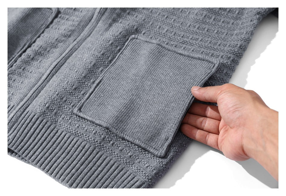 A hand demonstrates the rectangular rib-knit pocket on a gray textured cardigan.