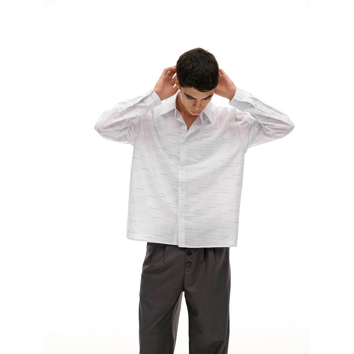 Model wearing a white button-up shirt with fine blue-gray horizontal dashes and a chest pocket, paired with charcoal