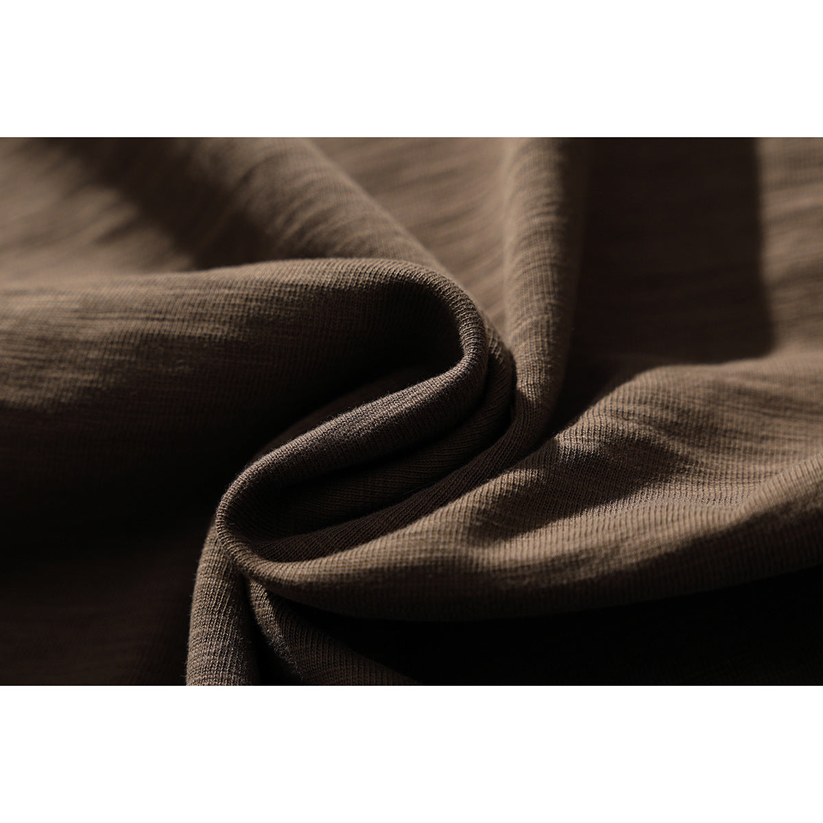 Close-up of brown heathered T-shirt fabric folded to show its texture and drape.