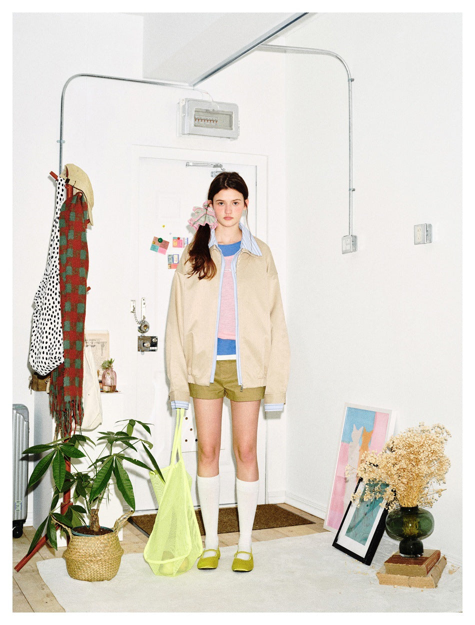 Front view of a model wearing a beige zip jacket with striped blue collar and cuffs.