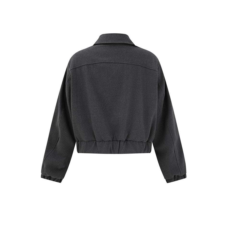 Back view of a cropped dark charcoal jacket with a pointed collar, long sleeves, and gathered cuffs and hem.