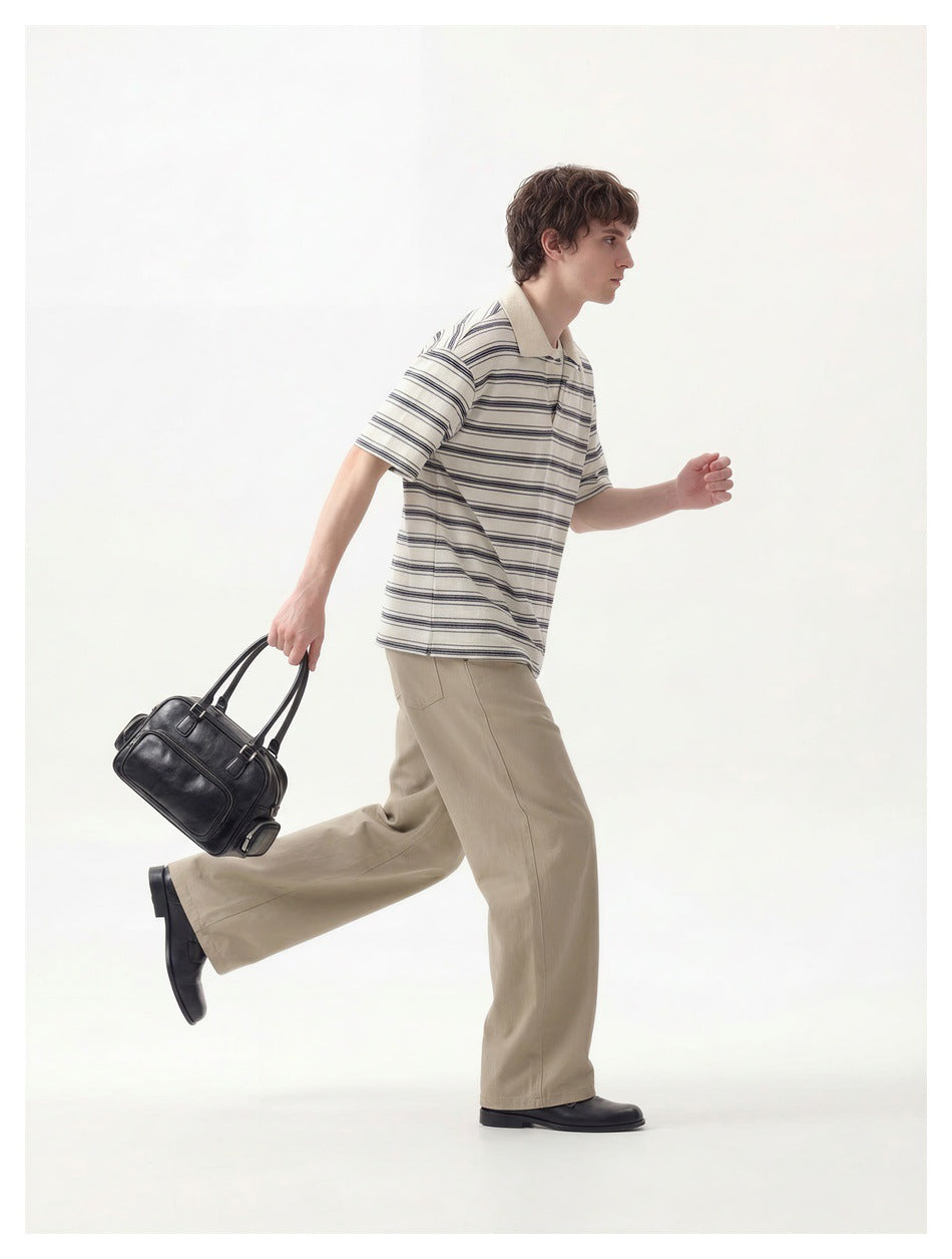 A man in motion wears an ivory polo with dark horizontal stripes and beige trousers.