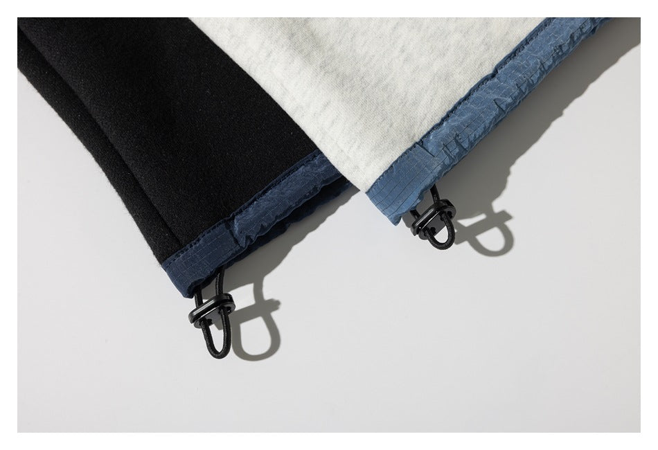 Close-up of gray and black pullover hems with blue trim and adjustable cord hardware.