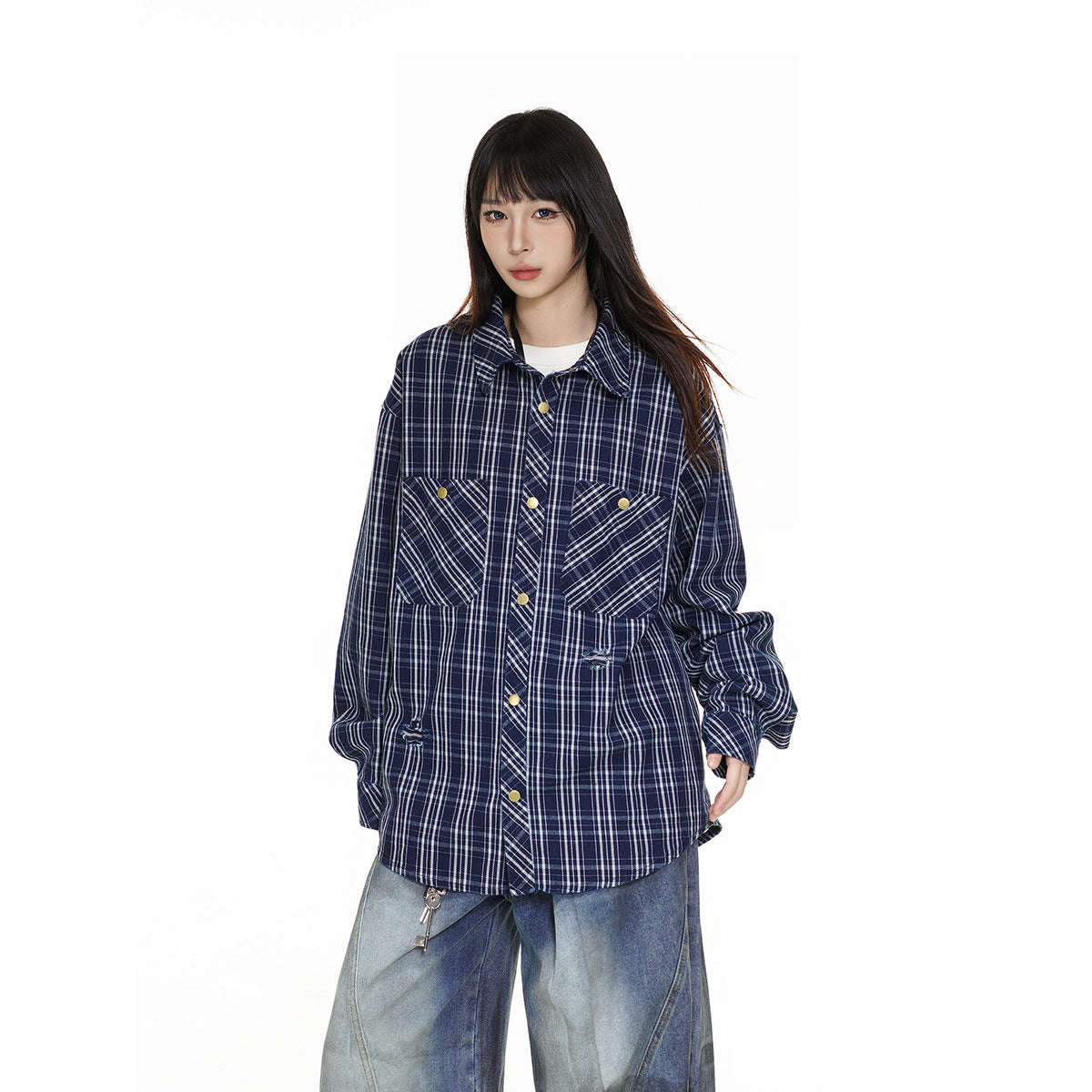 Closer view of a model wearing an oversized navy plaid shirt with angled flap chest pockets and gold-tone buttons.