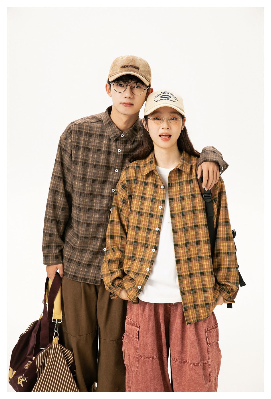 Two models pose together in brown and mustard plaid button-up shirts, shown from the front.