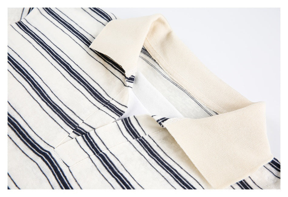 Close-up of an ivory garment with a folded cream collar and narrow navy stripes.