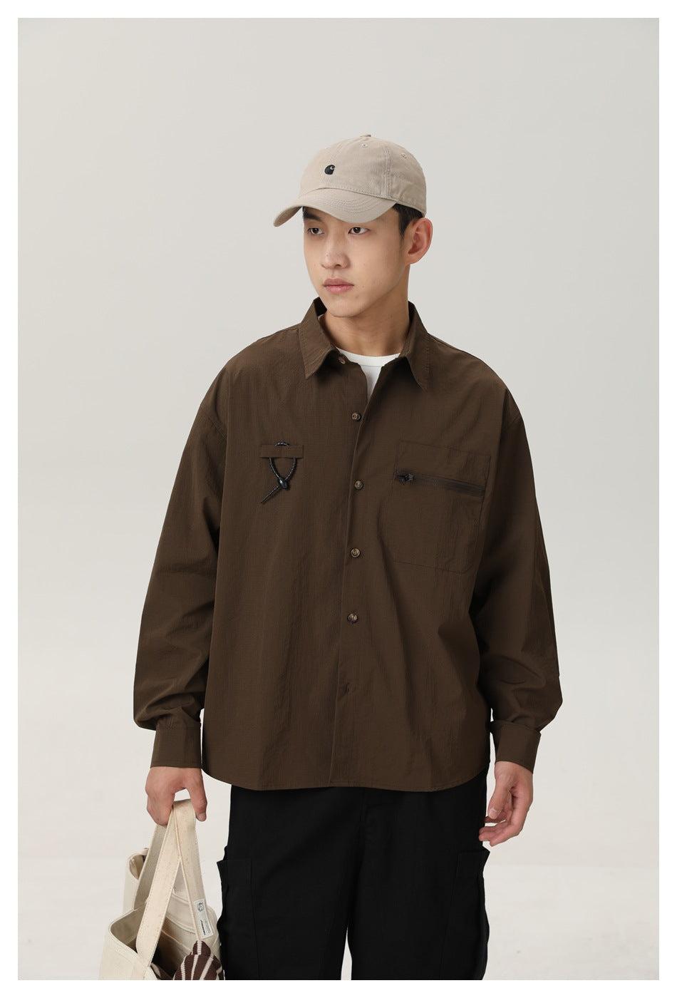 Model wearing a dark brown long-sleeve button-up shirt with a chest pocket and black cord detail.