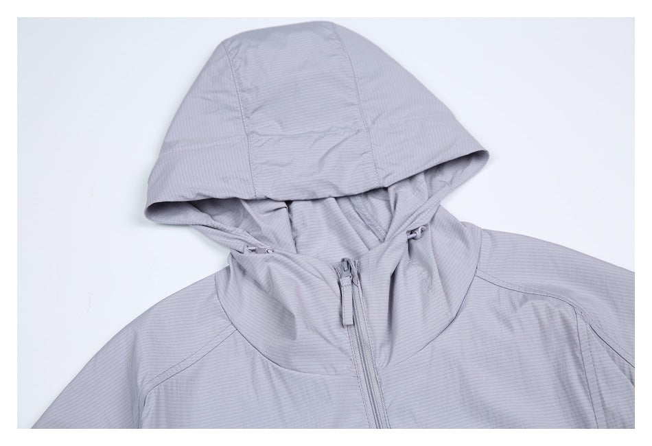 Close view of a light gray jacket's hood, drawcords, high collar, and front zipper.