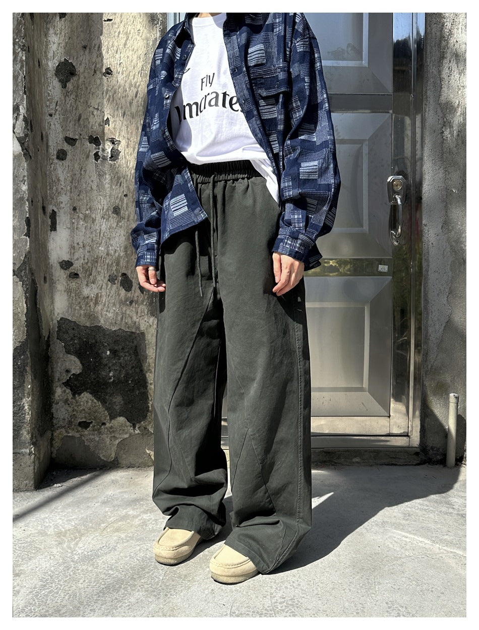 Model wearing dark olive wide-leg drawstring pants with a blue patterned overshirt.