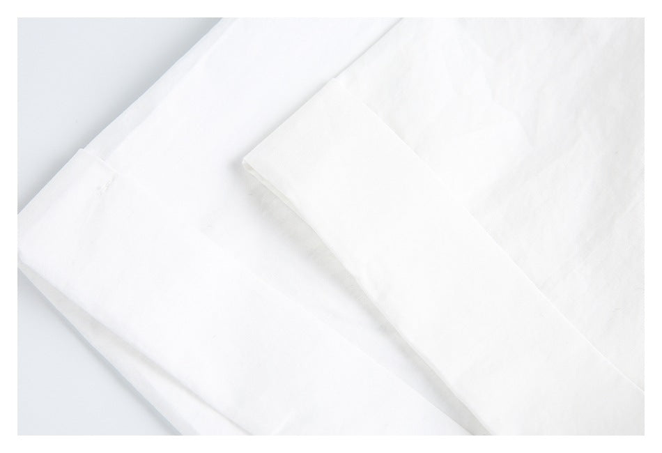 Overlapping sections of white garment fabric with visible seams and folded edges.