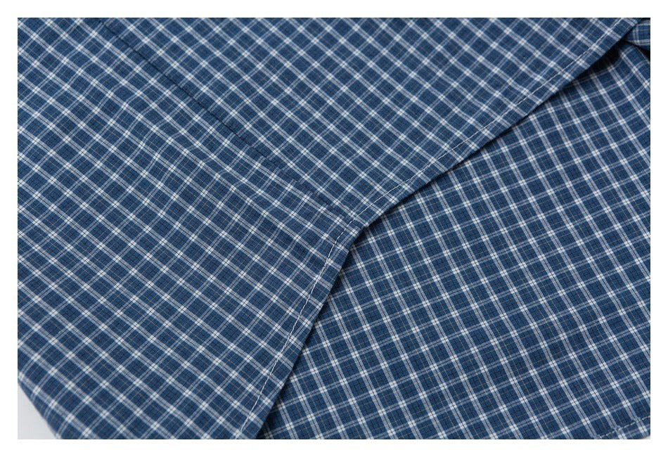 Close-up of blue plaid shirt fabric folded to show its checked pattern and stitching.