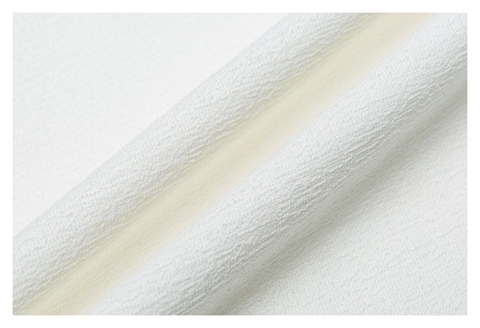 Extreme close-up of white garment fabric showing a raised folded edge and textured surface.