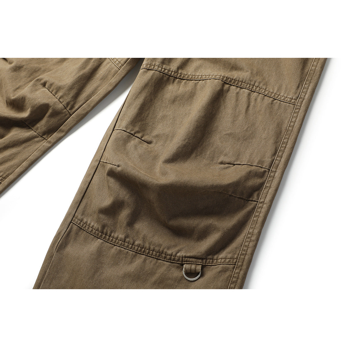 Close-up of tan-brown trouser legs showing reinforced knee panels and a small metal D-ring.