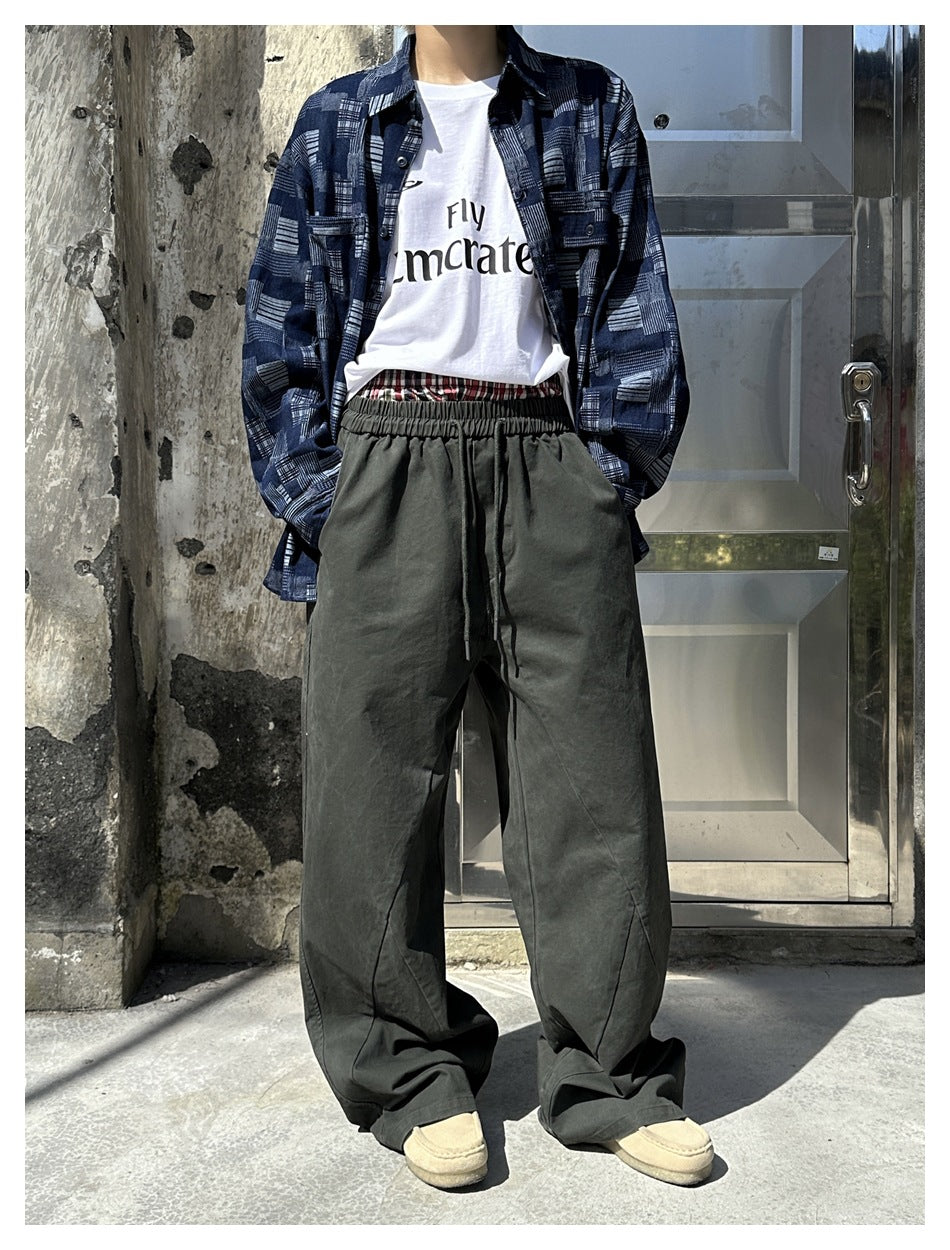 Model wearing charcoal-gray wide-leg drawstring trousers with a blue geometric-print overshirt.