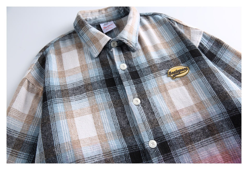 Close-up of the shirt's button front and yellow chest patch against blue, gray and beige plaid.
