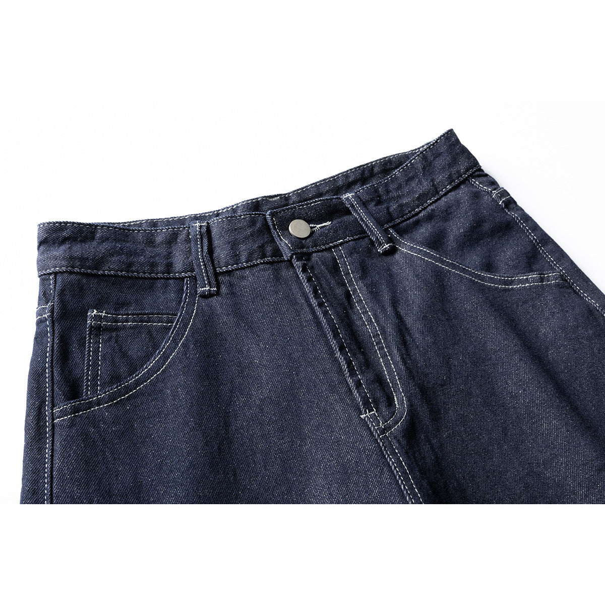 Close-up of dark indigo jeans showing the waistband, metal button, belt loops, fly, and front pocket stitching.