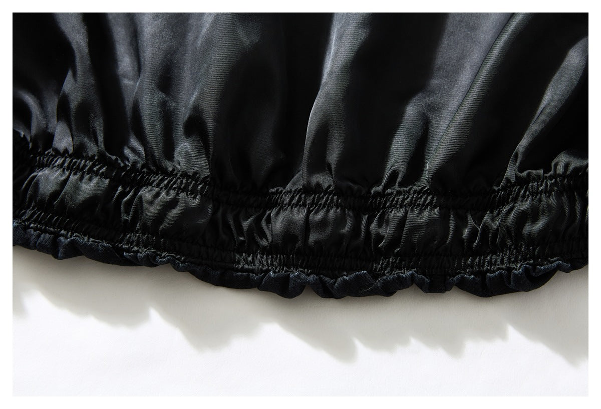 Close-up of black garment fabric with a gathered elastic seam and ruffled edge.